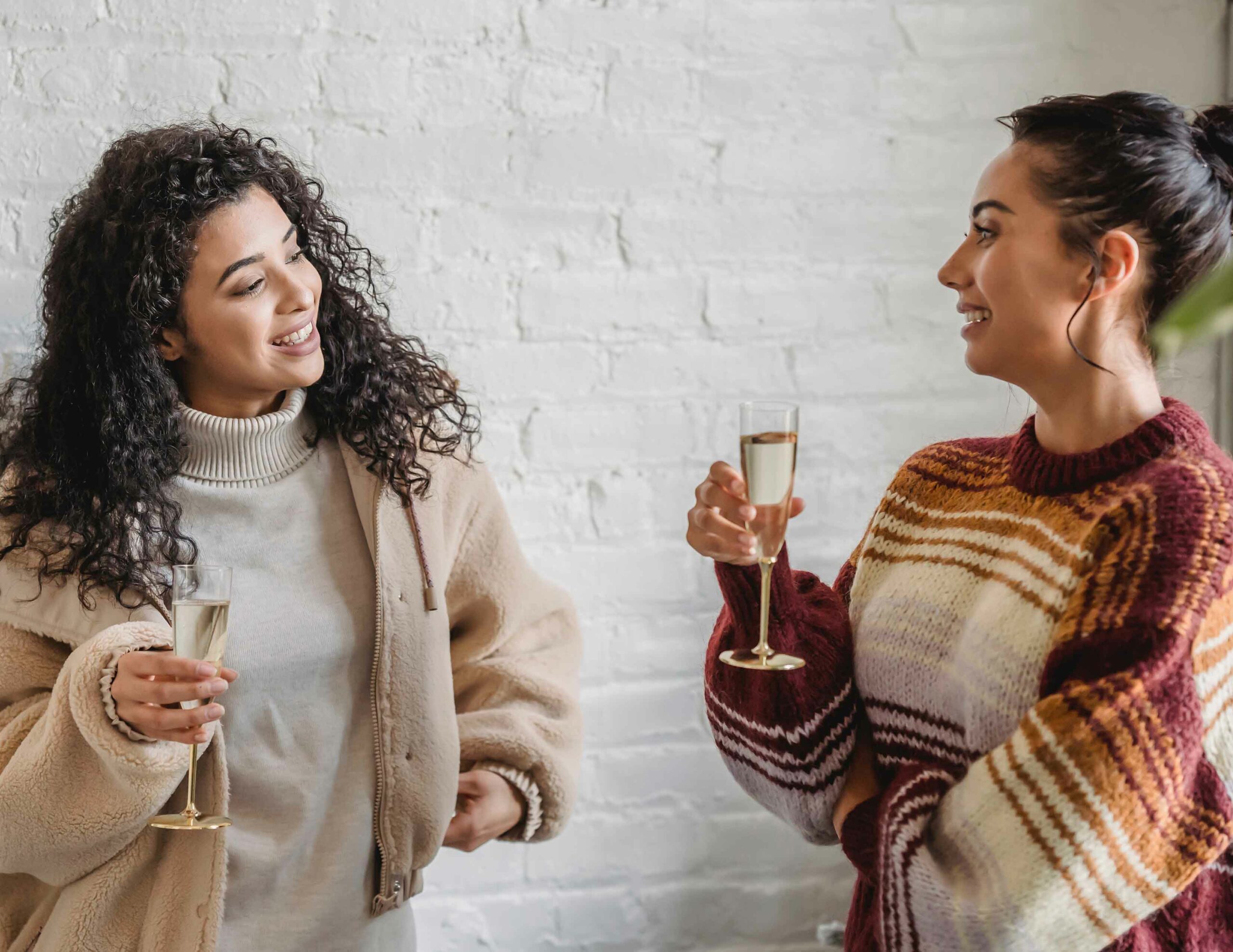 girl talking to each other holding a glass of champagne. Let EVERYONE know your plans